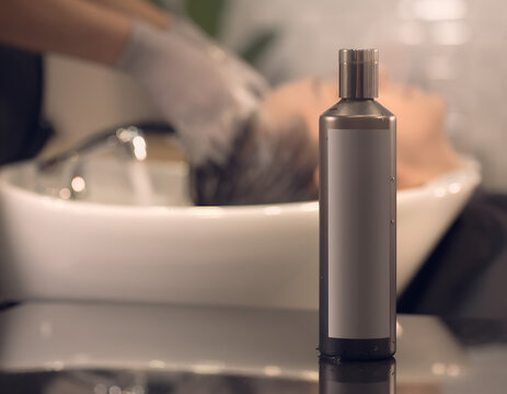Close-up view of a silver spray bottle on a reflective surface in a salon setting with a person washing hair