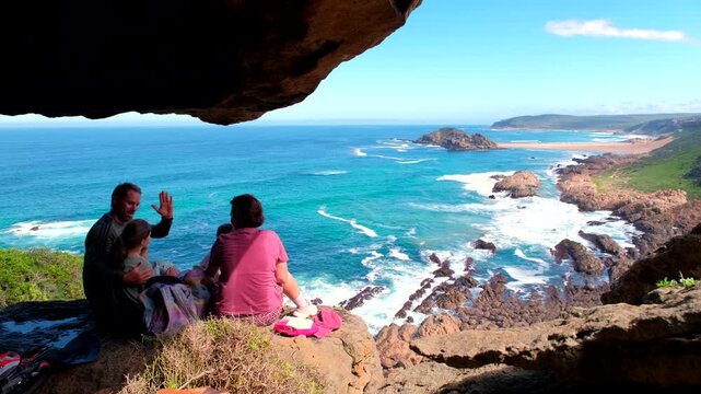 Happy family picnic at viewpoint on Robberg Nature Reserve overlooking coastline