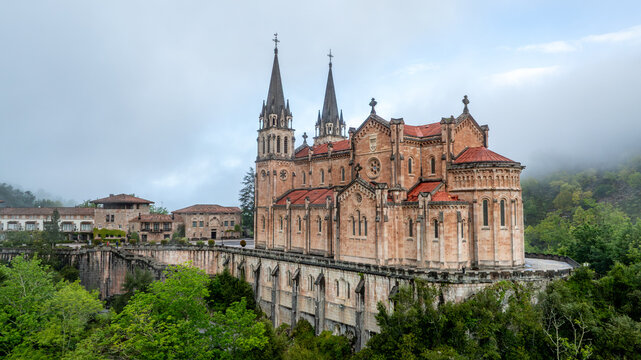 Aerial view of the Basilica's spires piercing through the ethereal mist, a symphony of stone and sky, Basilica de Santa Maria la Real de Covadonga, Cangas de Onis, Spain.