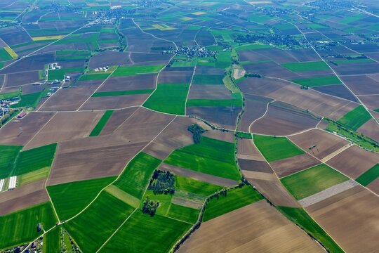 Aerial view of a patchwork quilt of verdant fields and earthy furrows, stitched together by thin roads, creating an intricate landscape, Wintzenheim-Kochersberg, Grand Est, France.