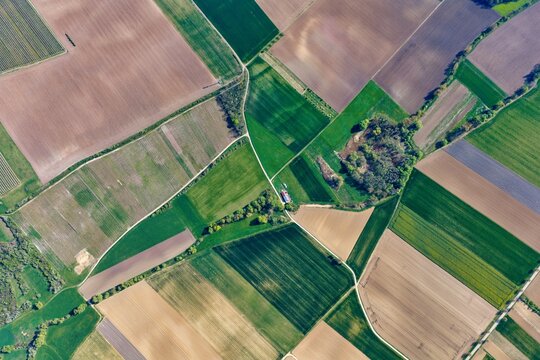 Aerial view of an intricate patchwork of agricultural fields, bisected by a winding stream and dotted with verdant copses, Wintzenheim-Kochersberg, Grand Est, France.