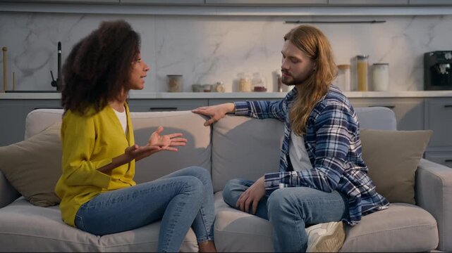Multiracial couple relationship problem conflict quarrel at home couch Caucasian man listen African American woman upset talking boyfriend girlfriend emotional husband wife discussing trouble indoors