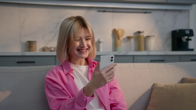 Happy excited Caucasian woman home sitting couch winning mobile phone bet smiling female girl celebrating achievement smartphone victory triumph yelling shouting joy offer discount online app indoors