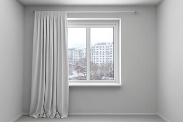 Fototapeta premium White curtain hangs beside a window with a city view in winter.