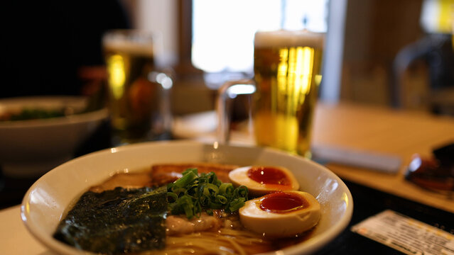 Close-up of Japanese Ramen Bowl with Soft Boiled Eggs and Beer