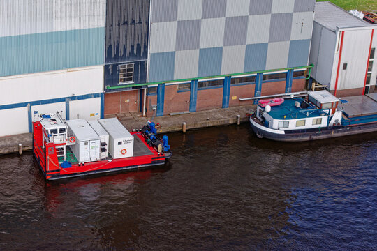 Wormer, Netherlands - 10 April 2026: Aerial view of a vibrant red electric pusher tug juxtaposed against the industrial backdrop of the Olam International cocoa factory.