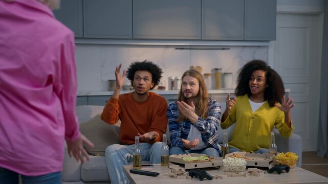 Glad multiracial students friends playing guessing game at home Caucasian woman showing pantomime gesturing explaining word fun African women men guys girls enjoying friendship weekend entertainment