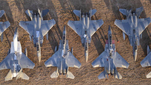 Tucson, United States - 30 January 2025: Aerial view of numerous powerful gray fighter jets starkly contrasted against the warm, sun-drenched desert earth.