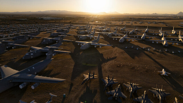 Aerial view of retired aircraft, bathed in the warm glow of the setting sun, amidst the vast, arid landscape of the Davis-Monthan Air Force Base, Tucson, United States.