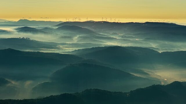 drone view wind turbine on Cau Dat hill, below is mountain ranges with fogs