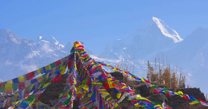 Reveal from prayer flags at Ama Yangri viewpoint, Nepal showing Langtang Himalayan range rising against a clear sky.