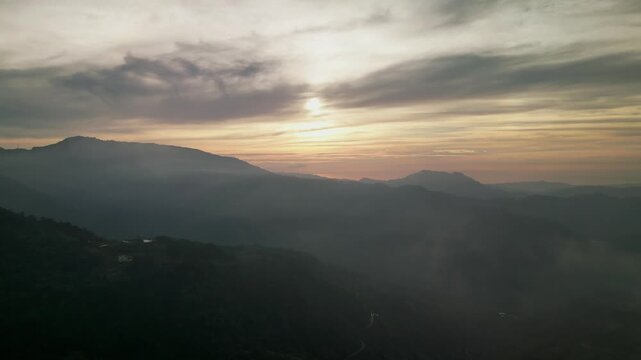 Aerial view of mountain ranges and rolling hills under a dramatic sunset sky in Benguet, Philippines with soft light and atmospheric haze