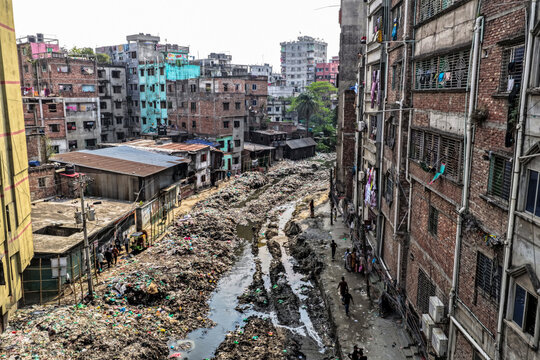 Keraniganj, Bangladesh - 11 April 2026: Aerial view of a grim ribbon of refuse and mud carving its path between densely packed, weathered residential buildings under a muted sky.