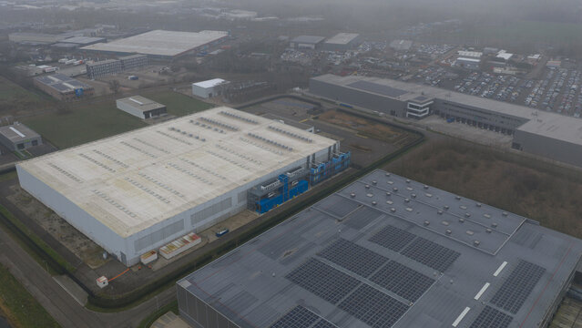 Roosendaal, Netherlands - 27 December 2025: Aerial view of stark, modern industrial buildings under a muted, overcast sky, highlighting geometric forms.