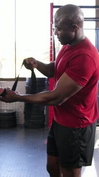 Vertical video: Taking strap from client, red tee coach wrapping wrist strap on bar at gym for lift