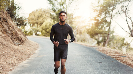 Obraz premium Man, running and earphones on mountain road for fitness, cardio development and training with podcast. Male person, runner and audio tech in nature for healthy body, outdoor challenge and music