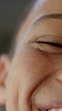 Vertical video: Smiling teen male squinting and laughing while leaning toward phone camera at home