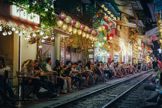 Hanoi, Vietnam - 06 October 2024: View of vibrant lanterns casting a warm glow on the bustling cafes lining the railway tracks along Pho Trung Hoa.