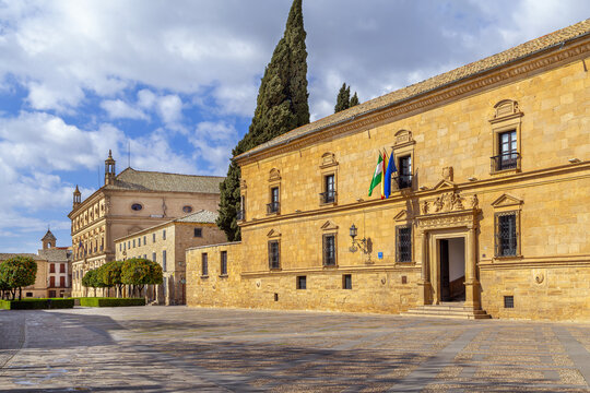 Dean Ortega Palace facade with fountain in distance at Ubeda, Spain. Renaissance architecture under cloudy sky at daytime