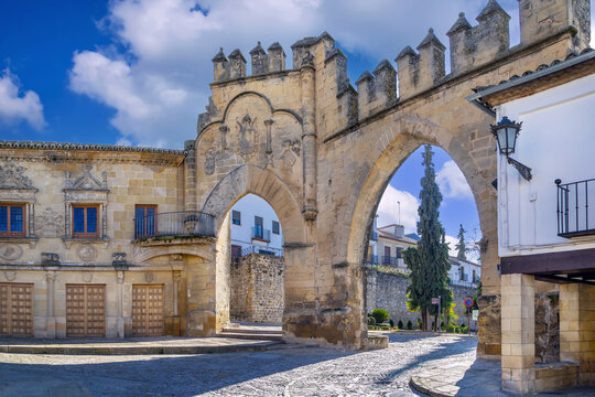 Arco de Villalar historic gateway in Baeza, Spain. Medieval stone arch and city wall under blue sky at daytime
