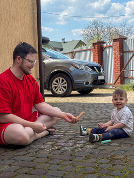 Father and toddler drawing with sidewalk chalk outdoors Copy Space