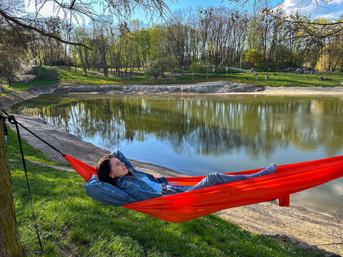 Relaxing in orange hammock by a lake in spring park Copy Space