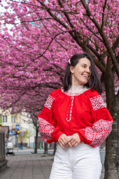 Smiling woman in red embroidered blouse under cherry blossoms Portrait