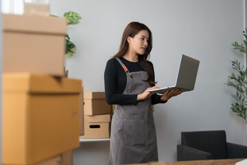 Naklejka premium Young woman managing online store checking orders on laptop