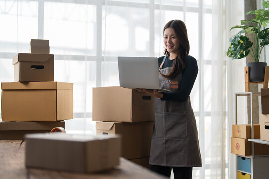 Young woman managing online business orders on laptop