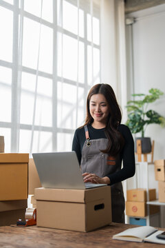 Young woman managing online store orders with laptop