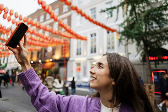 Tourist taking selfie with smartphone under red lanterns in Chinatown London