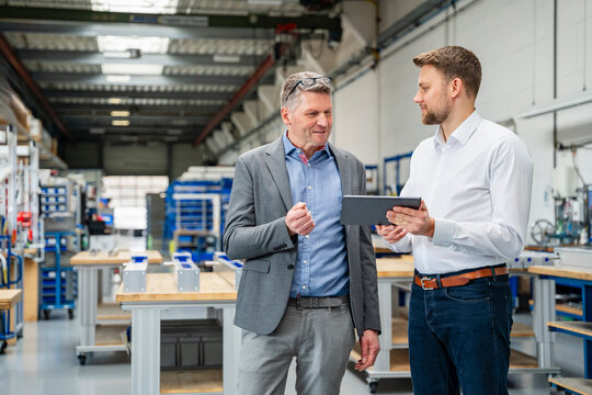 Manager and engineer discuss strategy with tablet in a factory