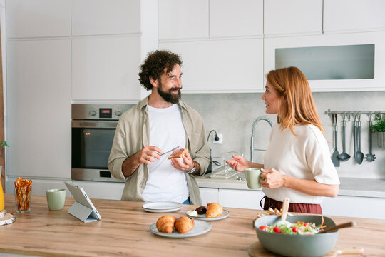Couple preparing and enjoying breakfast together in modern kitchen