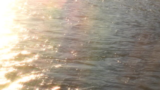 Sunny river ripples surface background with golden sun reflection shimmering on water