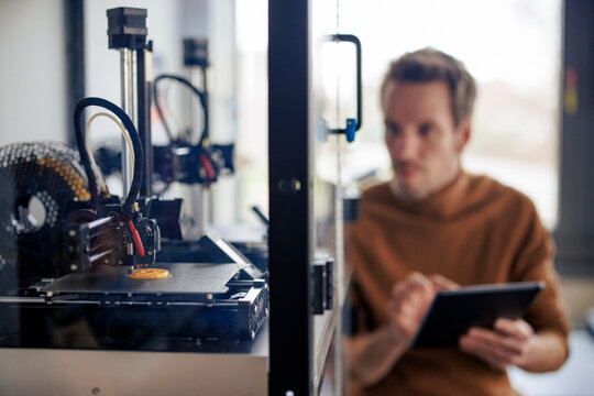 Engineer programming 3d printer machine at workshop