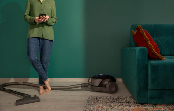Using smartphone next to vacuum cleaner in green living room