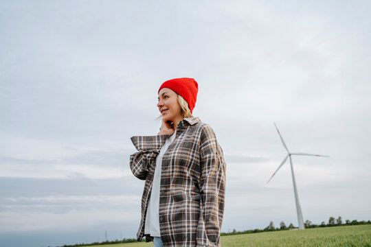 Woman wearing checked shirt standing at wind farm
