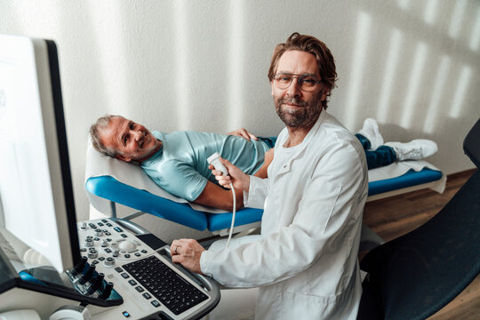 Doctor performing an ultrasound on a smiling patient in a clinic