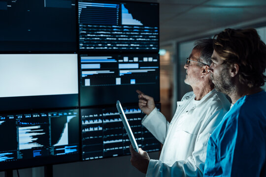 Doctor and surgeon analyzing medical data on hospital monitor