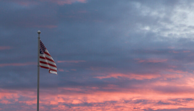 American flag flying on flagpole against a sunset sky