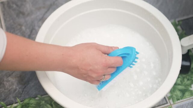 Preparing soapy water in basin is essential step for deep cleaning. Woman use brush to create rich foam for washing furniture. Proper preparing soapy water ensures effective dirt removal from surfaces