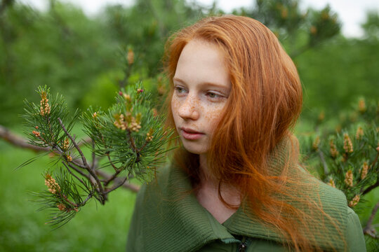 Thoughtful portrait with red hair and freckles outdoors in summer