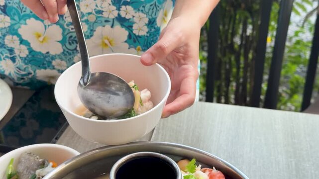 Serving Traditional Thai Tom Yum Seafood Soup into a White Bowl