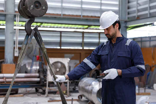Skilled industrial workers operate cranes to lift heavy materials in a factory, emphasizing precision, safety, and the efficient use of machinery in the production process.