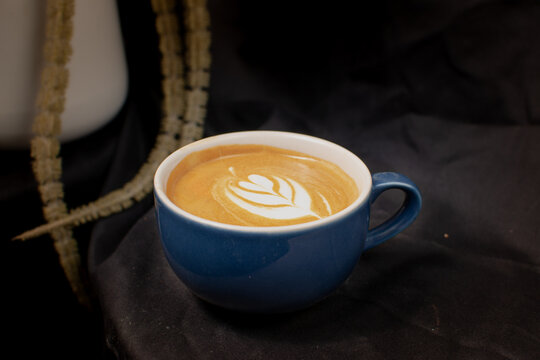 Landscape photo cup of coffee latte in a blue mug. served hot in the morning. isolated from black background. perfect for menu and advertising purpose
