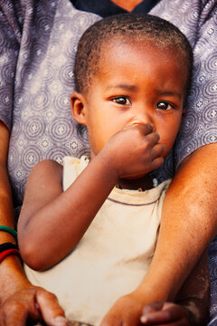 Basarwa San Child Portrait Being Held by an Adult old woman  Kalahari Botswana