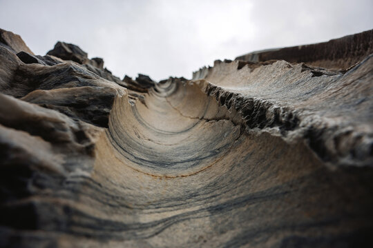 Looking up at Layered Rock Formations in a Natural Setting With Cloudy Sky in the Background During Daylight Hours