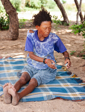Full portrait of an old Basarwa San woman siting on a blanket on the ground in the Kalahari.