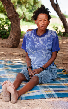 Full portrait of an old Basarwa San woman siting on a blanket on the ground in the Kalahari.