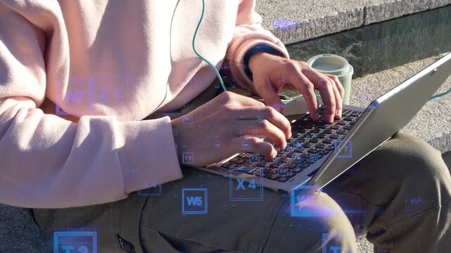 Person typing on a laptop keyboard outdoors with digital code overlay. Digital nomad and remote work concept with data processing